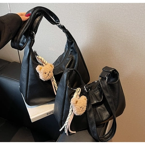 Macro shot of two black crescent hobo bags in pebbled PU leather with cute bear charms