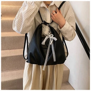 Detalle de bolso tote de cuero negro con elegante lazo de encaje y adorno de perlas