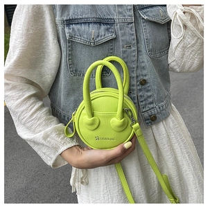 Détail du mini sac vert fluo avec texture litchi et bandoulière porté par un mannequin