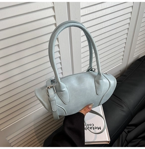 Detail of light blue semi-oval handbag showing the zipper closure and adjustable strap