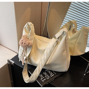 Detail of off-white pleated leather crossbody bag with a cute brown plush bear charm
