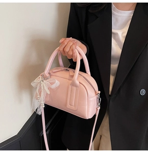 Detail of pink Boston bag with pearl bow charm and smooth leather texture finish