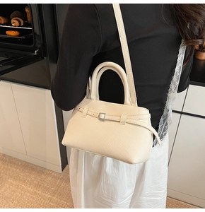 Detailed view of cream leather bucket bag with litchi texture and shoulder strap