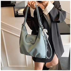 Detalle de bolso tote de cuero granulado azul claro con colgante de encaje y perlas