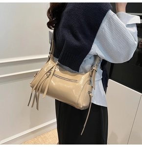 Detalle del bolso bandolera vintage beige con cremalleras de borlas y acabado de charol