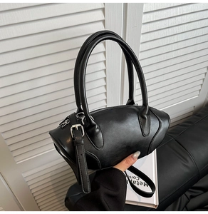 Close-up of black leather bowling bag with silver buckle straps and smooth texture