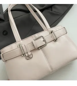 Dettaglio di borsa in pelle beige con cinturini decorativi e fibbie in metallo argento