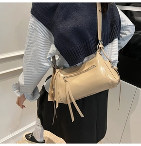 Vista detallada del bolso beige con cremalleras de flecos y correa con ojetes