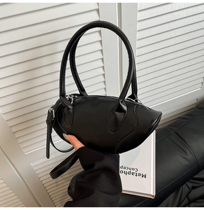 Close-up of a minimalist black oval handbag with sleek leather texture and dual handles