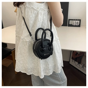 Détail d'un mini sac bandoulière rond noir en similicuir grainé avec logo argenté chic