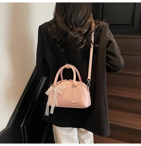 Detailed shot of a pink leather boston bag with lace bow and pearl accent on a model
