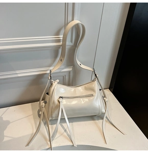 Detalle del bolso en cuero aceitado blanco crema con cremallera y flecos largos