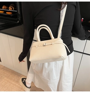 Close-up of off-white leather bucket bag with pebble texture and metallic buckle details