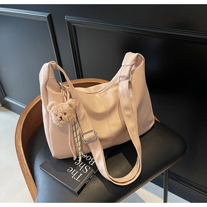 Close-up of pink oversized faux leather tote bag with teddy bear charm on wood chair