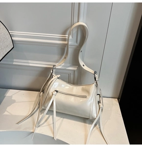 Detalle de bolso de hombro en charol blanco crema con flecos largos decorativos