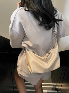 Chic beige glossy shoulder bag with tassel, stylish hobo style shown on model