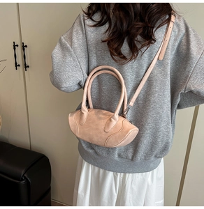 Detail of light pink textured leather handbag showing crossbody strap and dual handles