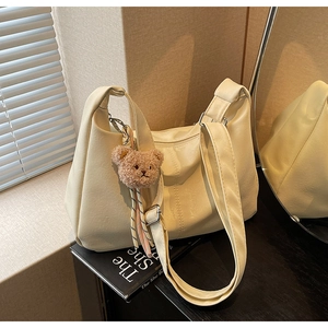 Close-up of cream hobo bag with adjustable silver buckle and cute brown bear charm