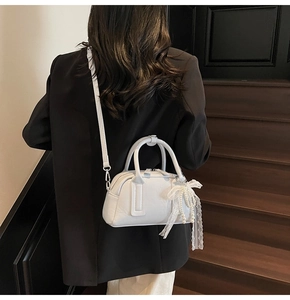White Boston handbag with pearl lace bow detail shown on a model in a modern interior
