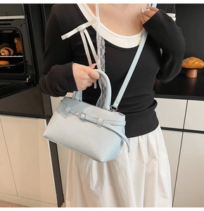 Close-up of a light blue pebble leather bucket bag with top handle and shoulder strap