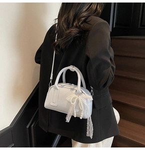 Light blue Boston bag with pearl lace bow charm shown on a black blazer outfit