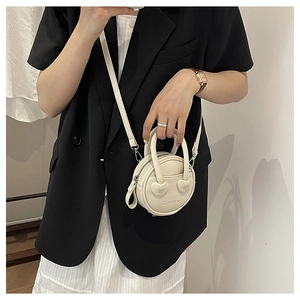 Detail of cream mini round bag with heart patches and textured PU leather finish