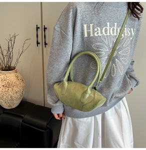 Detailed view of avocado green leather handbag with curved design and detachable shoulder strap