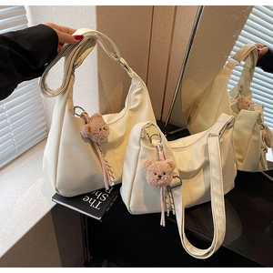 Detail view of cream white soft leather tote bags in two sizes with plush bear charms