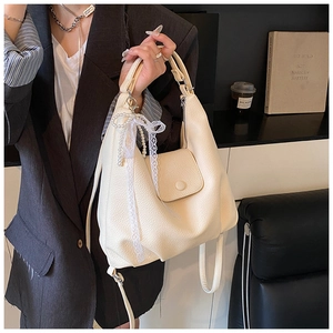 Detail of cream-white lychee leather tote with lace bow and pearl pendant charm