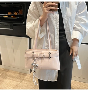 Dettaglio borsa a spalla in pelle rosa chiaro con ciondolo a fiocco e fibbia argentata