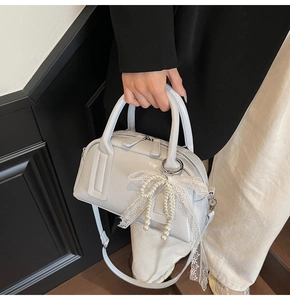 Detail of light blue patent leather Boston bag with pearl bow and lace trim decoration