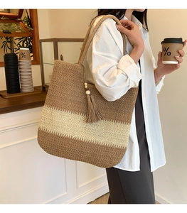 Close-up of woven straw tote bag with brown stripes and tassel wood bead charm