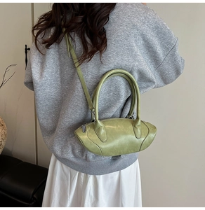 Model wearing avocado green mini crossbody handbag with curved silhouette and silver zip