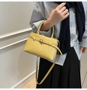 Detail of yellow pebbled leather bucket bag with top handle and adjustable shoulder strap