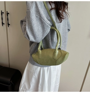 Olive green geometric crescent bag in textured suede shown from a side view on model