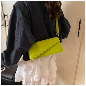 Detail of neon green envelope bag showing the geometric flap and silver buckle on model