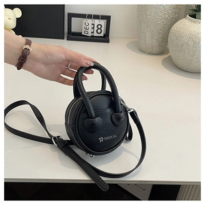 Vue détaillée d'un mini sac rond noir à texture litchi avec bases de poignée en forme de cœur