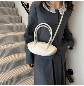 Detailed shot of an off-white oval crossbody bag showing leather texture and strap