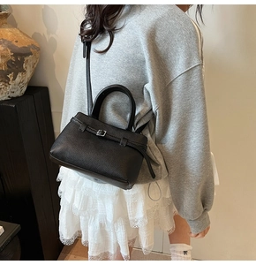 Detailed view of black lychee grain leather bucket bag with adjustable strap and buckle