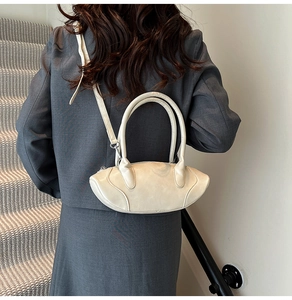 Chic cream white crossbody bag shown on a model in a stylish city staircase scene