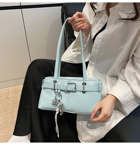 Dettaglio della borsa a secchiello celeste con ciondolo a orso argentato e manici eleganti
