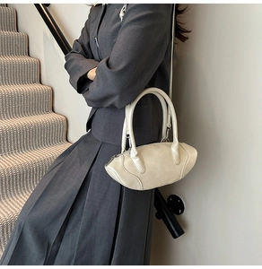 Chic cream white oval handbag featuring smooth PU leather with long shoulder strap in use