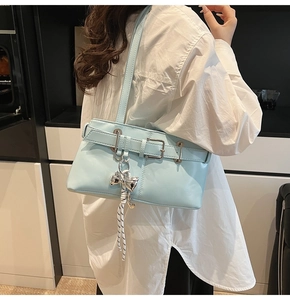 Borsa sottobraccio azzurra in ecopelle con ciondolo a fiocco indossata da modella