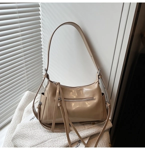 Detalle de bolso de hombro en charol brillante beige con detalle de cremallera de borla