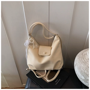 Primer plano de bolso tote beige con textura de lichi y adorno de encaje y cuentas