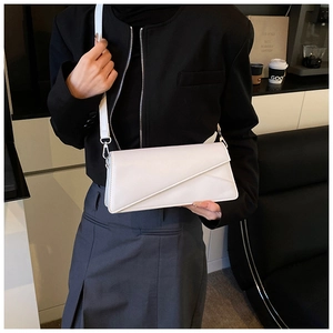 Detail of white minimalist baguette bag with diagonal flap cut and silver metal buckle