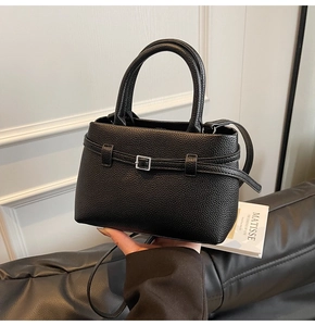 Close-up of black pebble leather texture and silver buckle on a luxury bucket bag