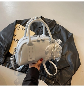 Detail of light blue Boston handbag with pearl bow charm and smooth leather texture