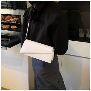 Detail of white leather baguette bag with geometric flap on a shoulder strap