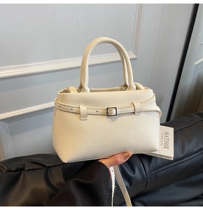 Detail of cream white pebbled leather handbag with adjustable strap and metallic buckle